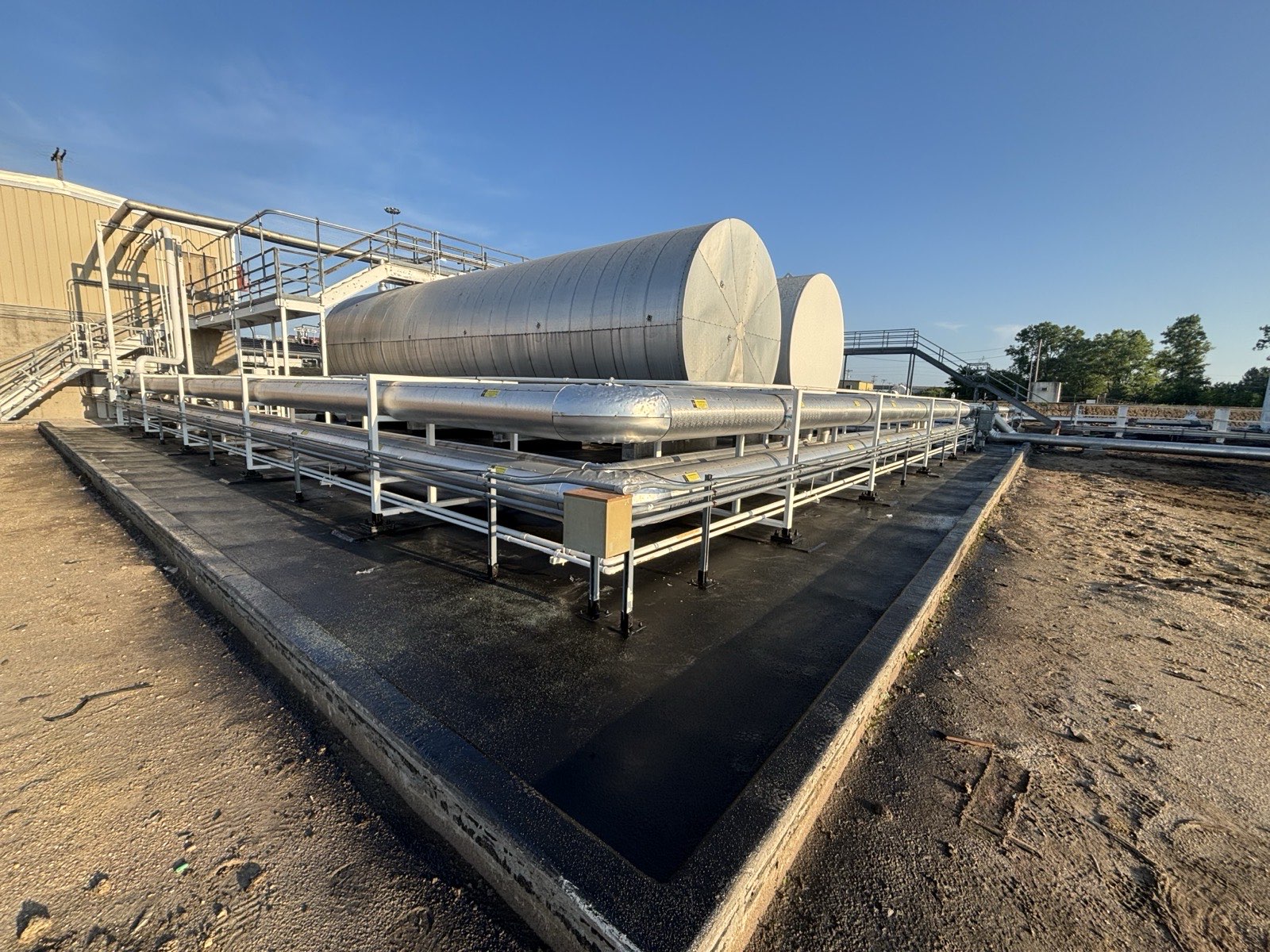 Completed PHX6700 polyurea containment lining around compressor-oil tanks, piping, supports, and perimeter curbs in the containment area