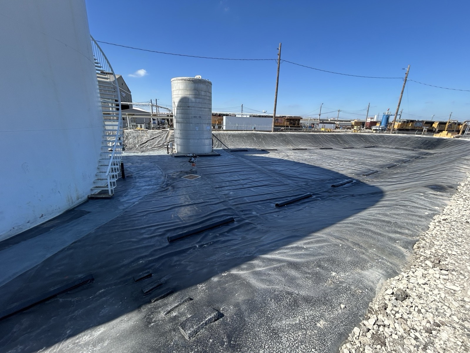 Completed prefabricated containment liner installed across the basin floor around a lube-oil storage tank