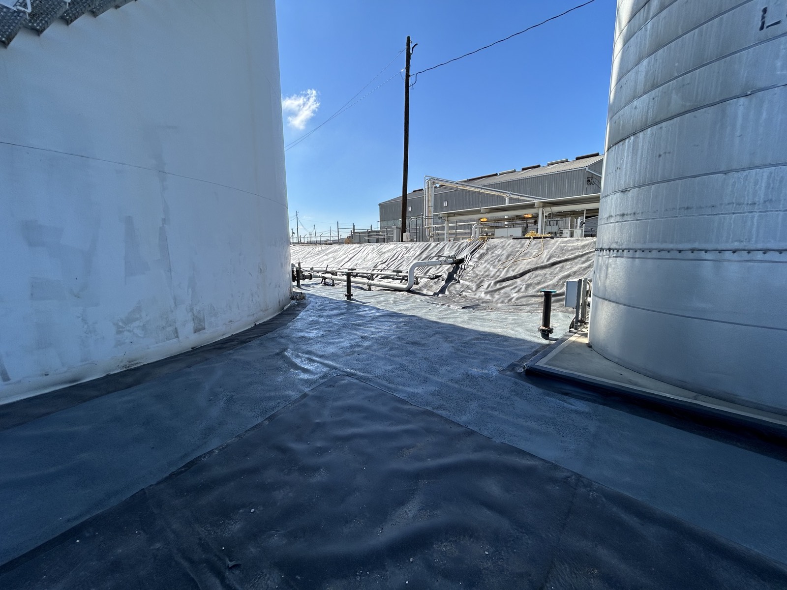 Continuous containment liner installed between storage tanks with sealed field seams and transitions