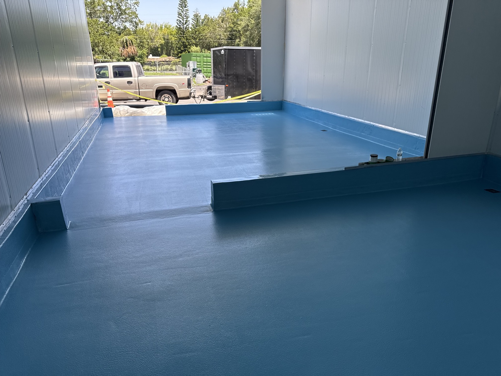 Seamless blue cooler floor with a floor drain and coved wall base in a meat market