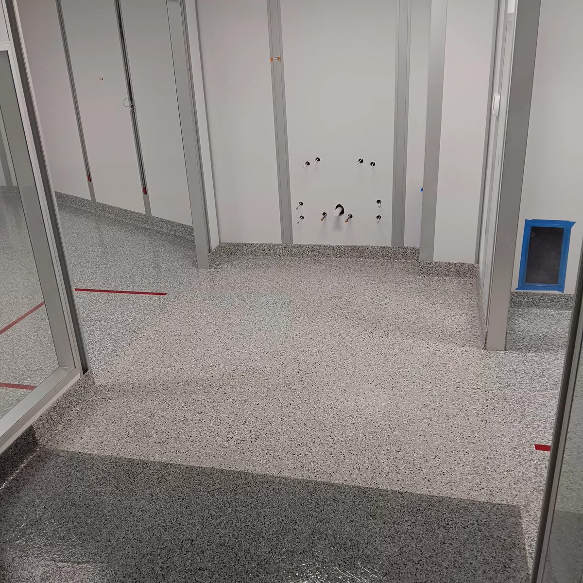 Color-separated flake clean room zones meeting at a glass partition with integral cove base