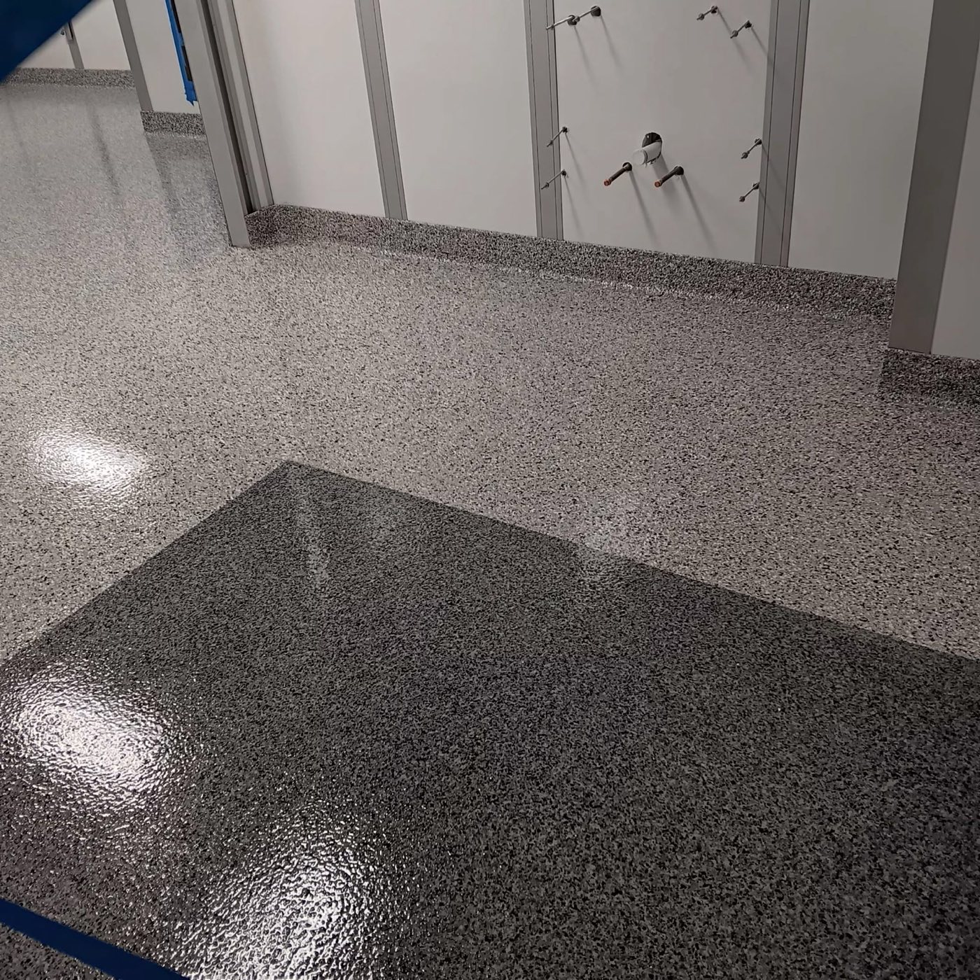 Two-tone flake clean room floor with a darker transition zone and integral cove base at a glass partition wall